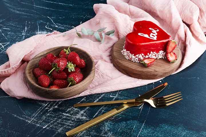 strawberries and a red heart cake on a table