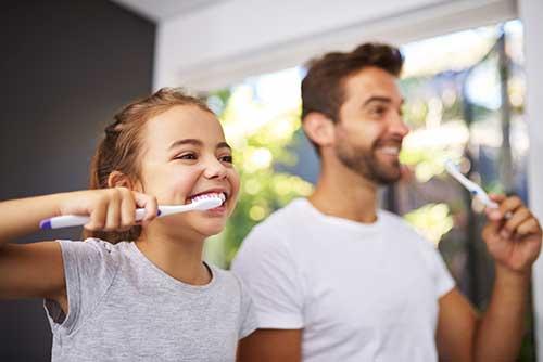 girl and father brush teeth
